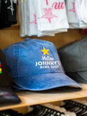 Blue cap with a star and Mellow Johnny's on it on a wooden shelf with blurred background