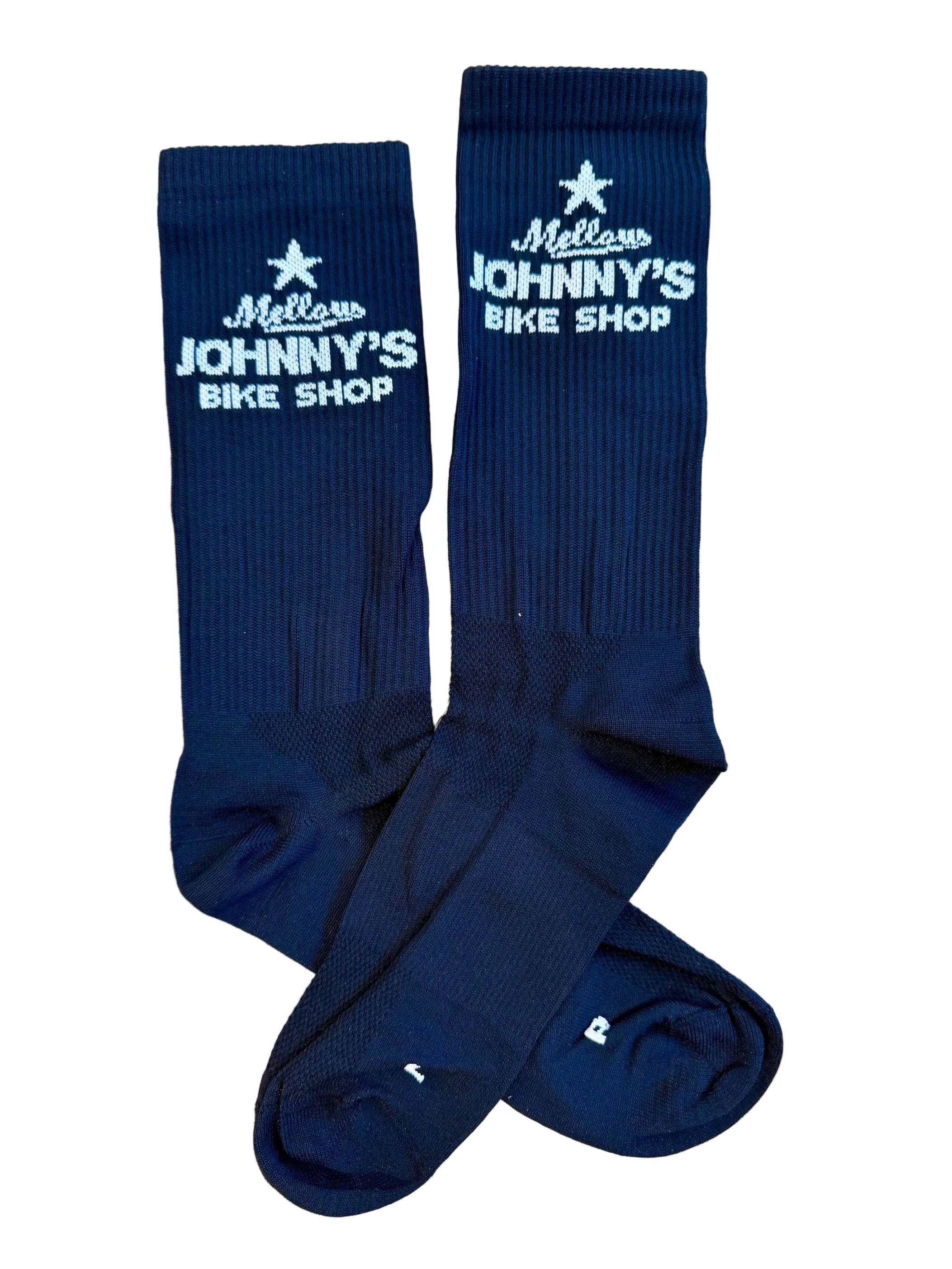 A pair of black crew socks with white embroidered text reading 'Mellow Johnny's Bike Shop' and a star logo, laid flat on a white background.