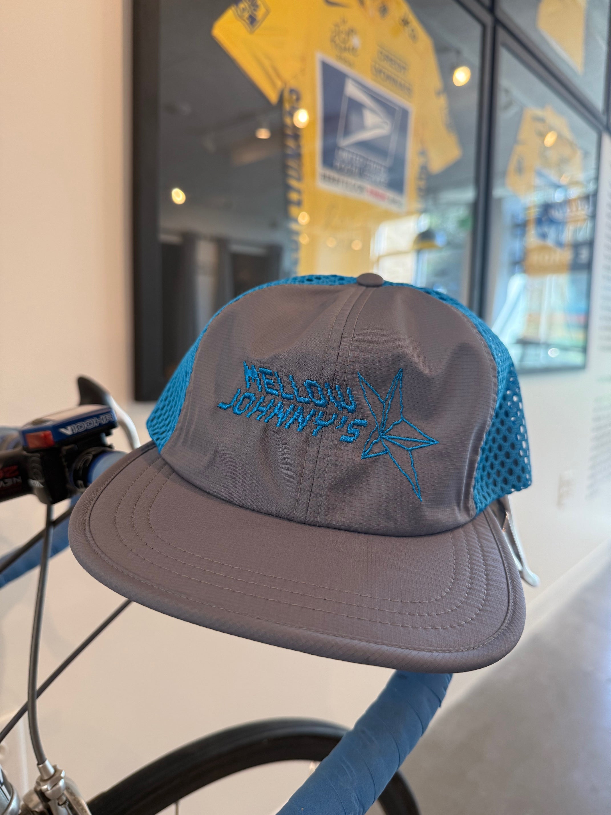 Gray cap with blue brim and embroidered logo on a bicycle