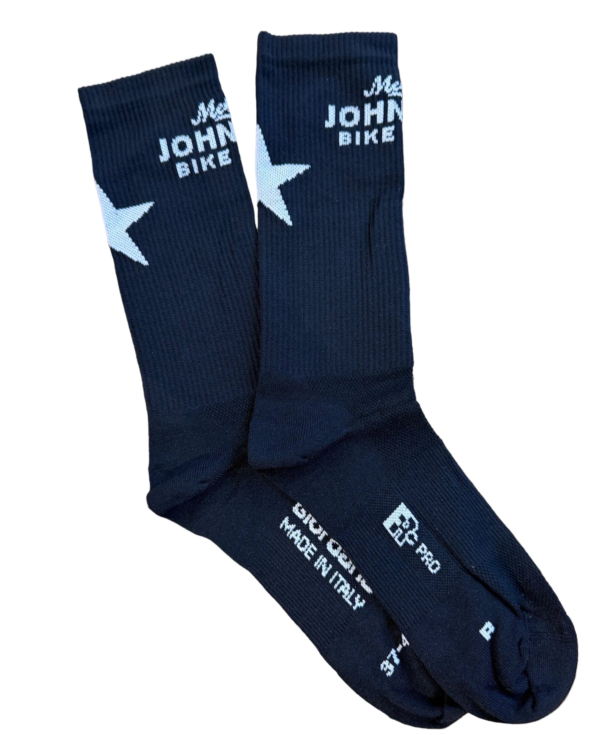 A pair of black crew socks with white printed graphics, including a star and 'Mellow Johnny Bike Shop' branding, laid flat on a wooden surface.