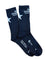 A pair of black crew socks with white printed graphics, including a star and 'Mellow Johnny Bike Shop' branding, laid flat on a wooden surface.