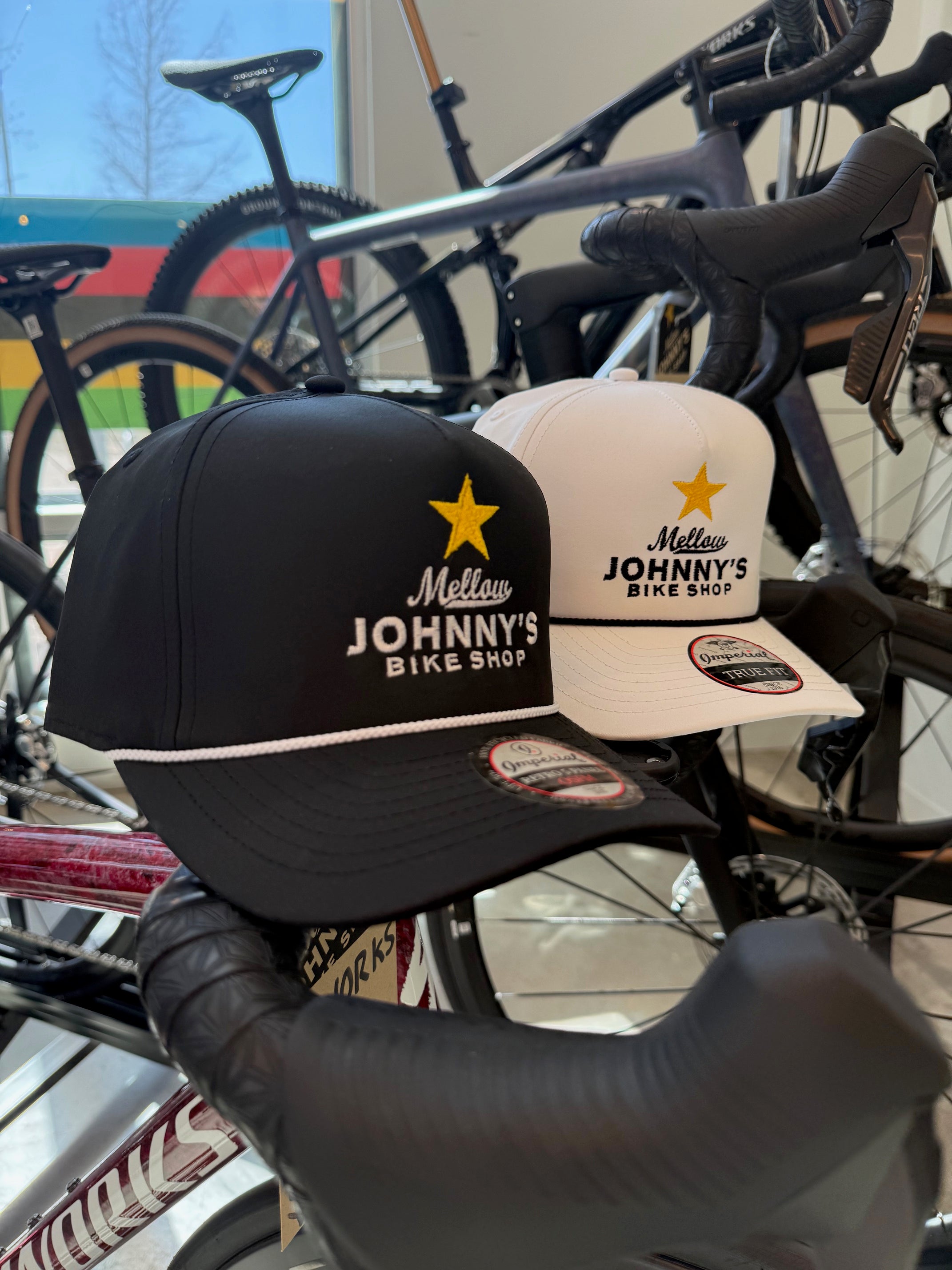 Two caps with 'Mellow Johnny's Bike Shop' branding on a bicycle handlebar.