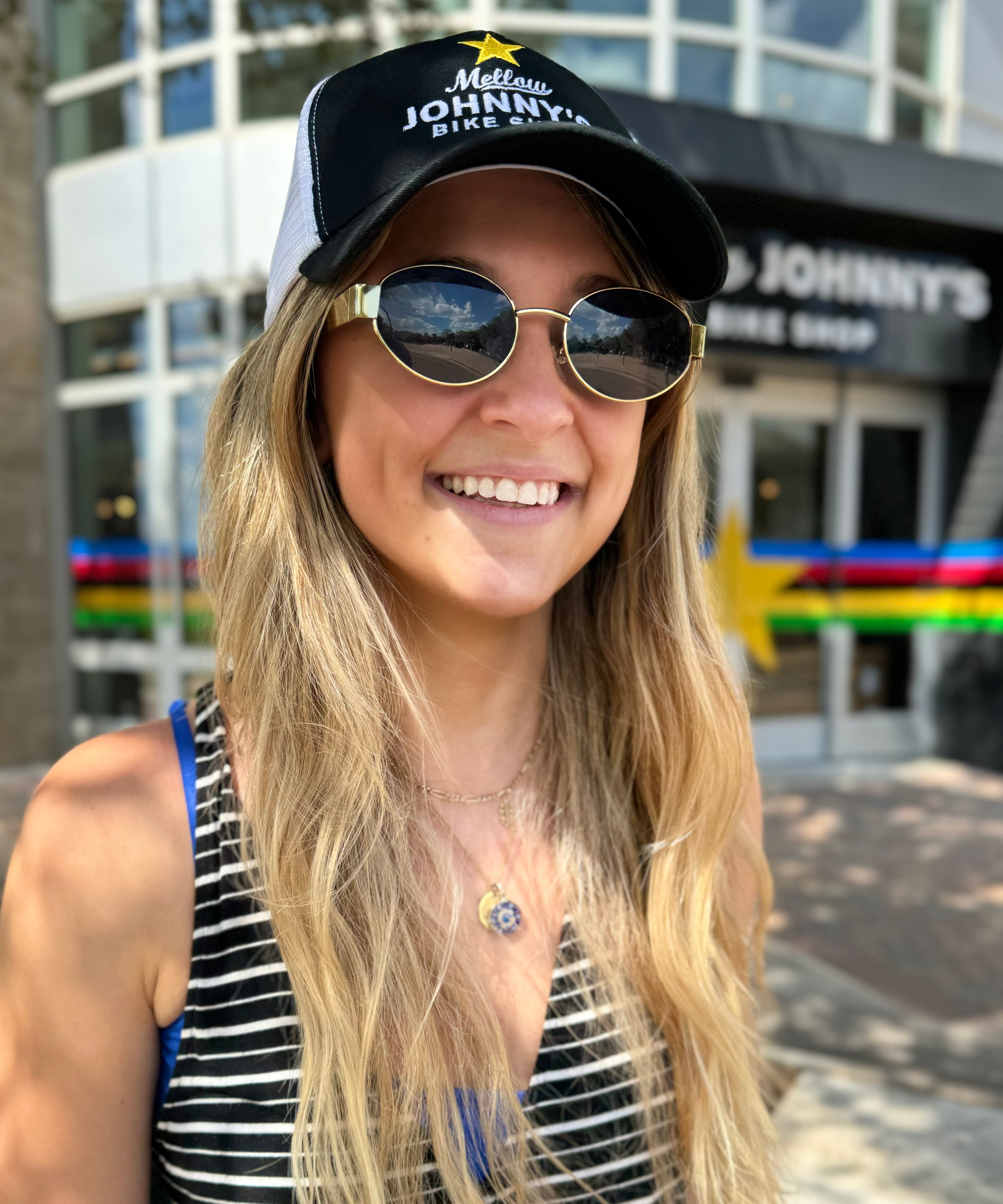 A person wearing a white and black 6 panel mesh snapback trucker hat with 'MELLOW JOHNNY'S' branding on the front.